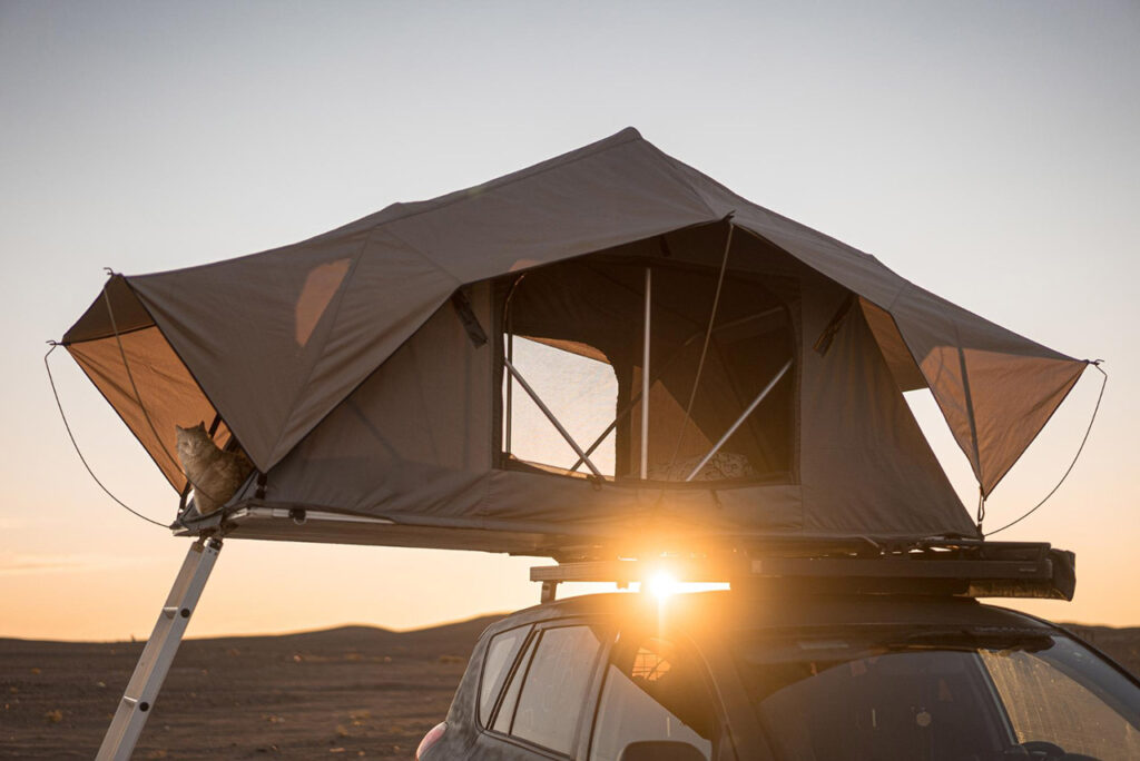 rooftop tent for camping on the roof rack of an off-road car in a desert at sunset